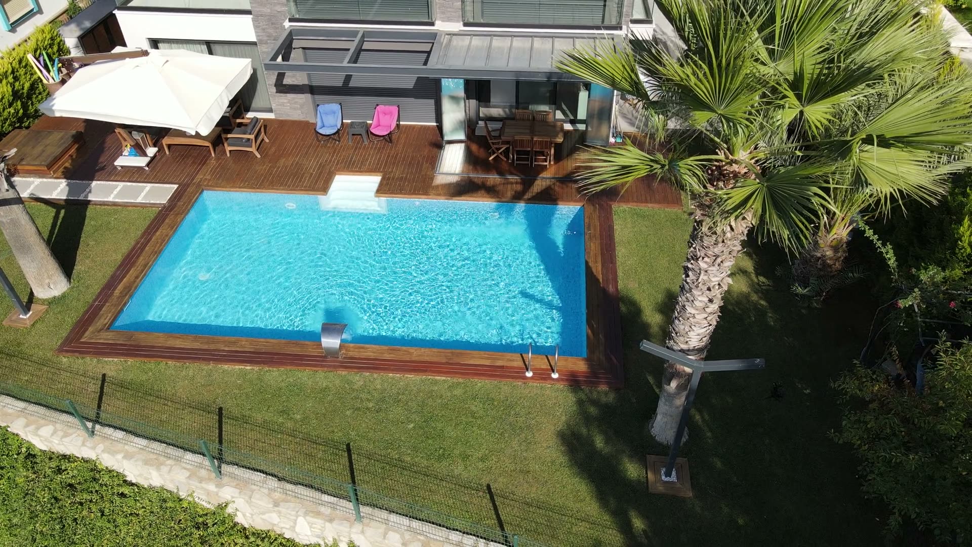 Palmiyeli bir villa bahçesinde tamamlanmış havuzun kuşbakışı görünümü