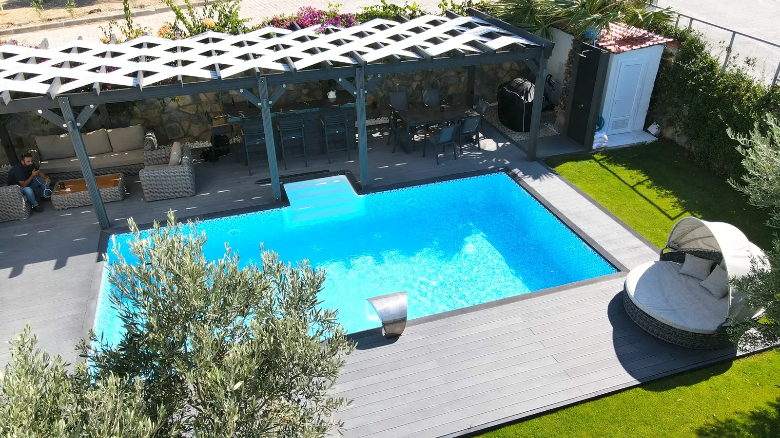 Ahşap deck ve pergolayla çevrelenmiş geniş havuz