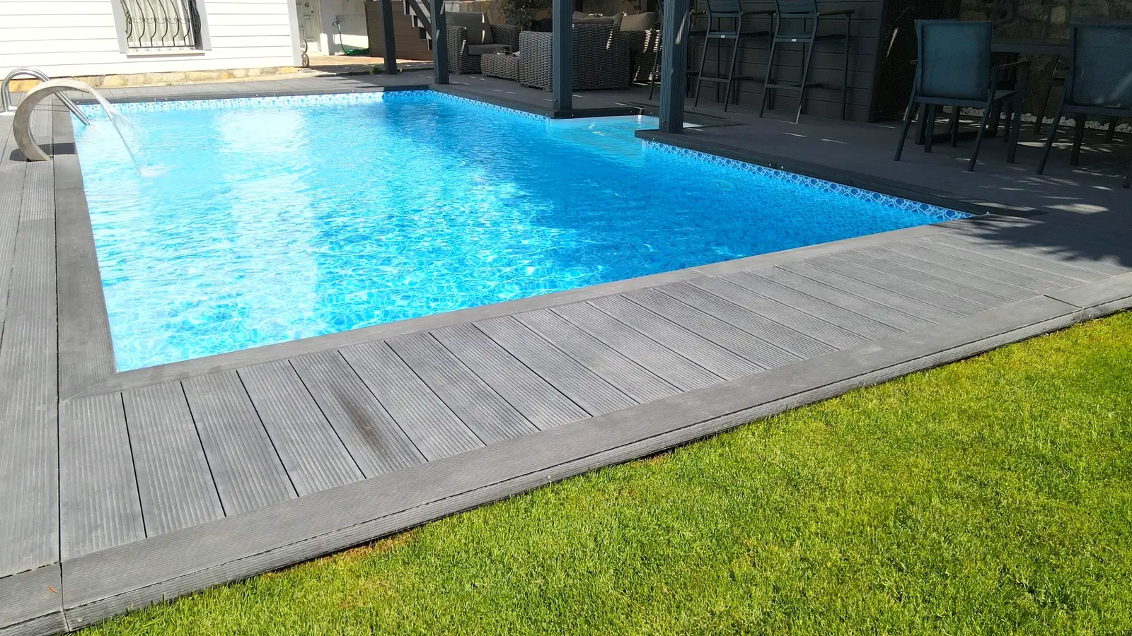 Ahşap deck ve pergolayla çevrelenmiş geniş havuz