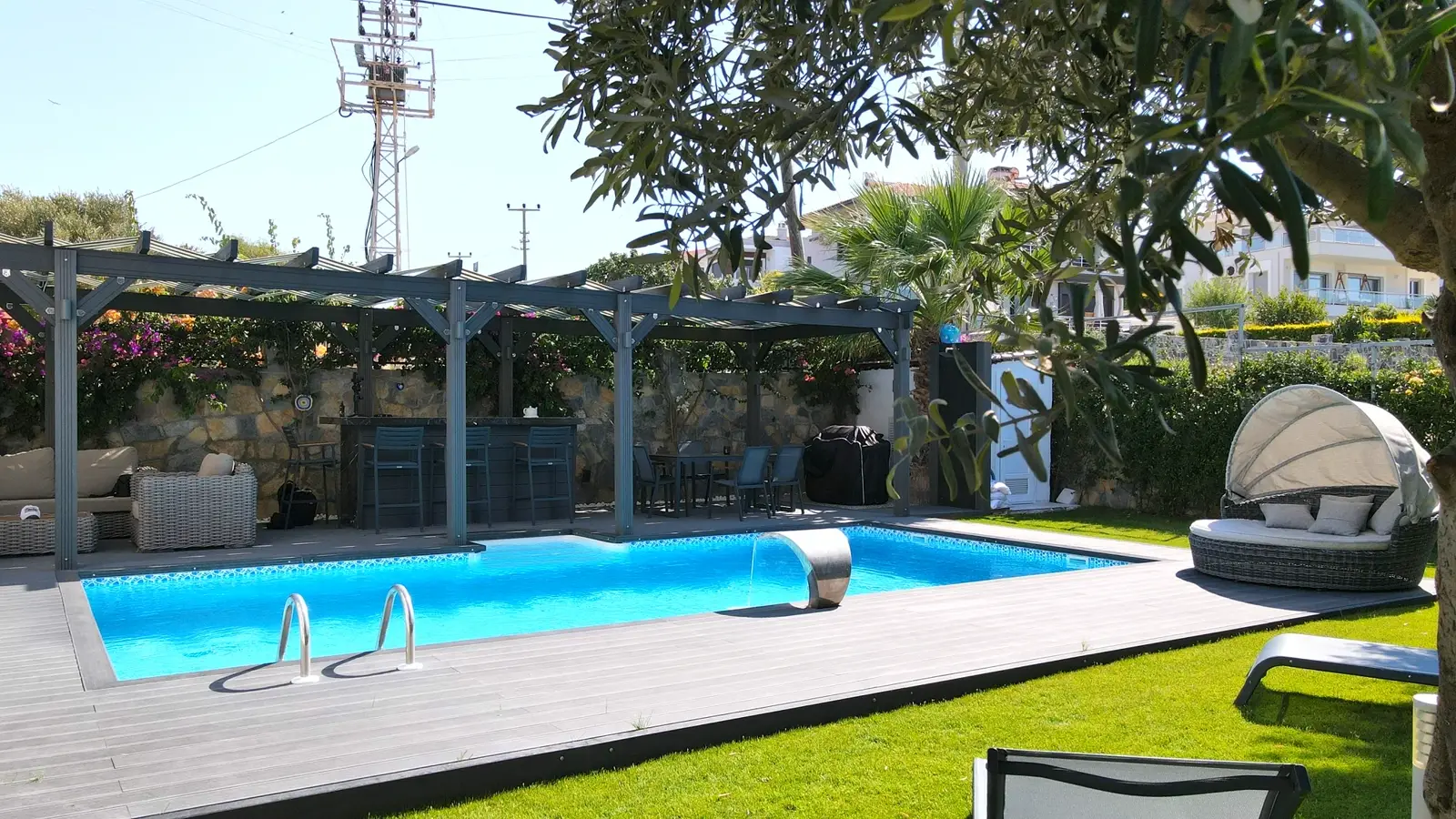 Ahşap deck ve pergolayla çevrelenmiş geniş havuz