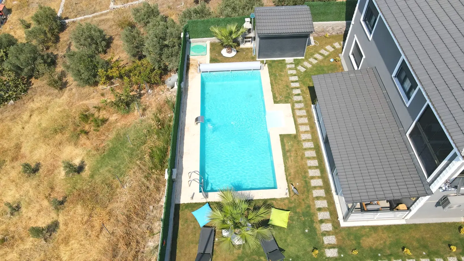 Modern villa bahçesinde çim zeminli havuz düzeni