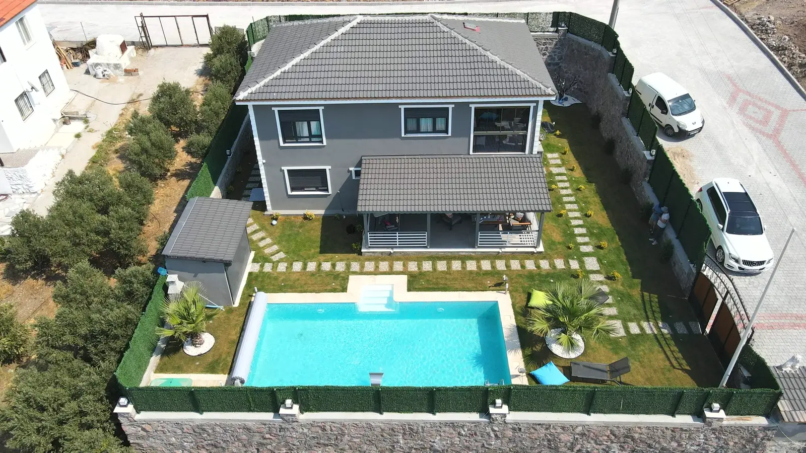 Modern villa bahçesinde çim zeminli havuz düzeni