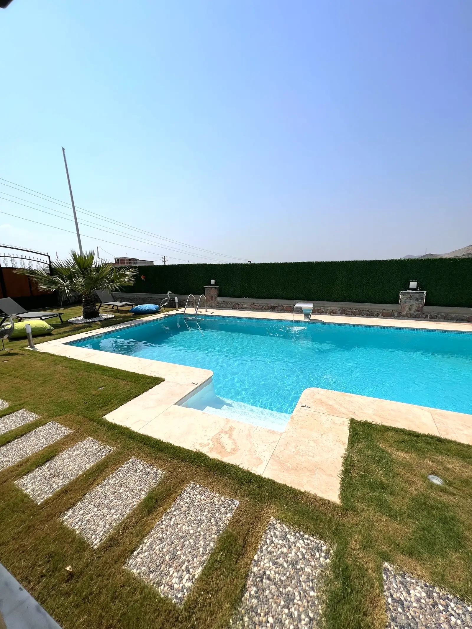 Modern villa bahçesinde çim zeminli havuz düzeni