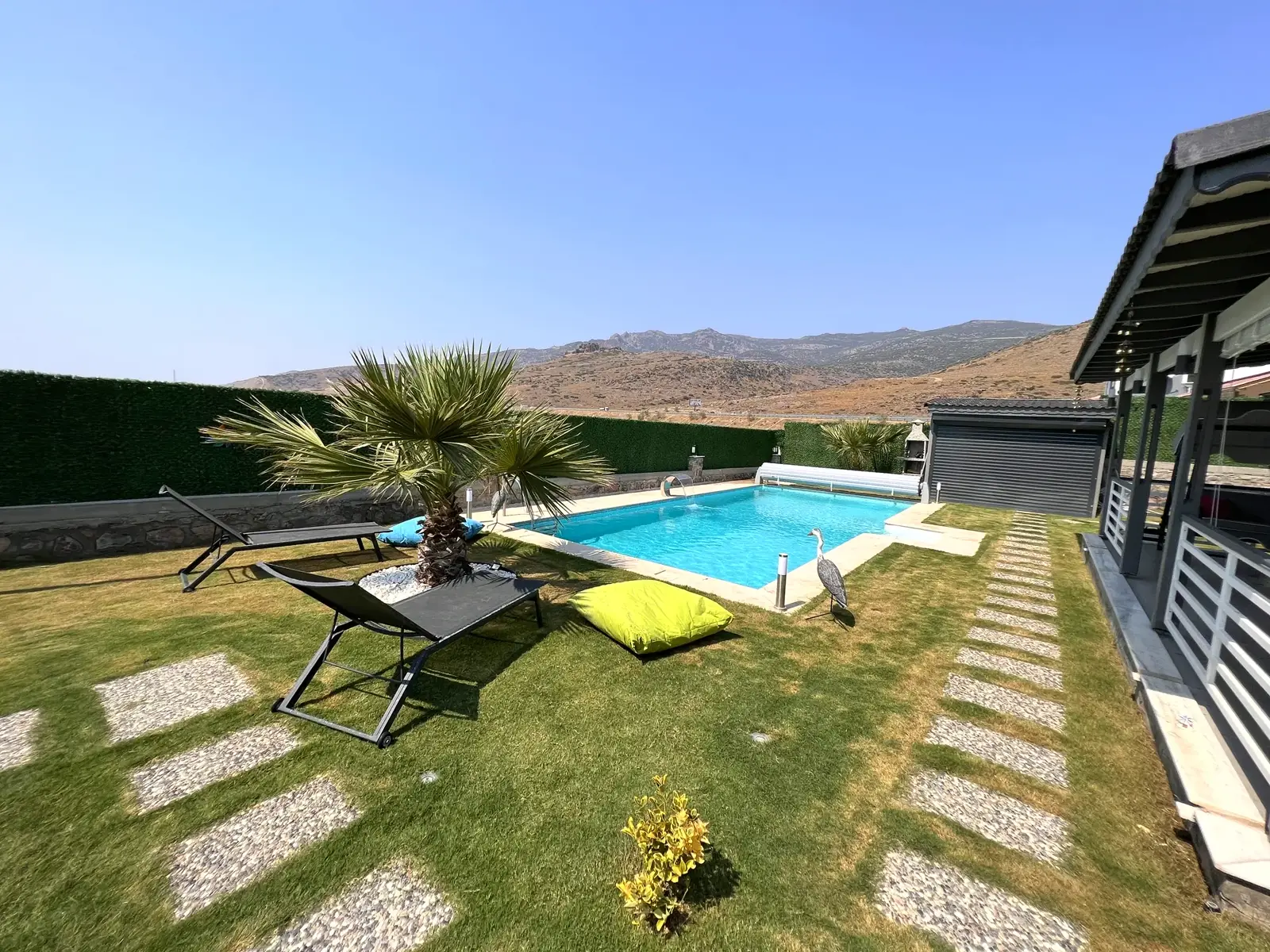 Modern villa bahçesinde çim zeminli havuz düzeni