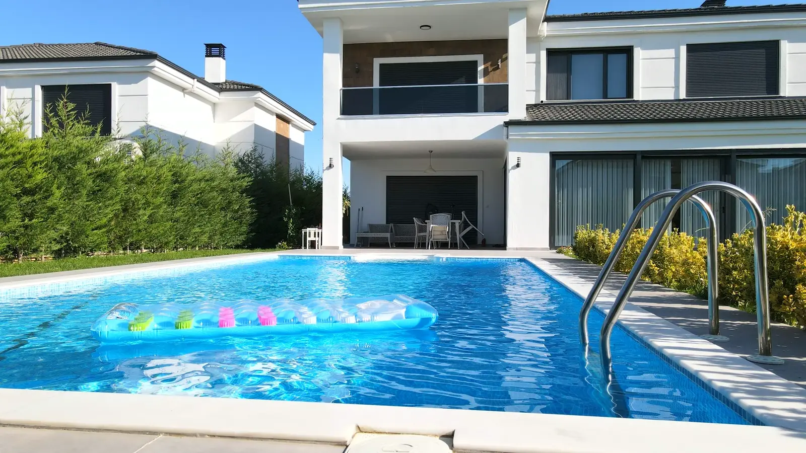 Modern villa bahçesinde havuz ve oturma alanı
